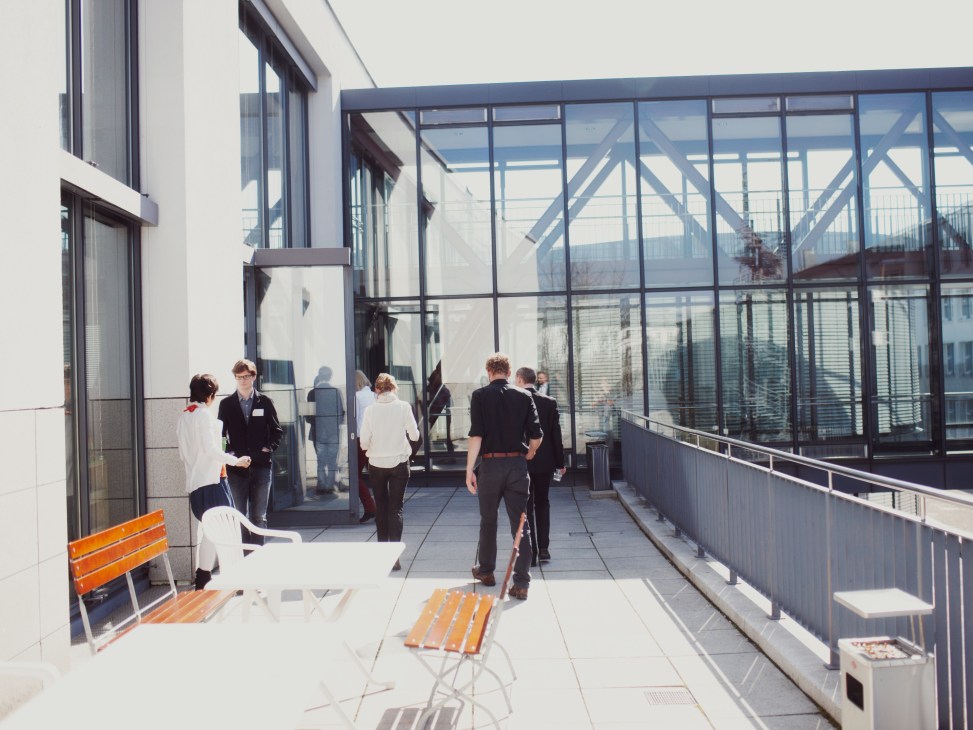People relaxing on an outdoor terrace with orange benches at the Goethe-Institut Munich headquarters.