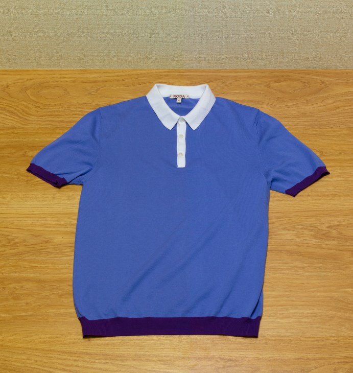 Roda blue short-sleeve polo shirt with white collar and burgundy trim on wooden floor.
