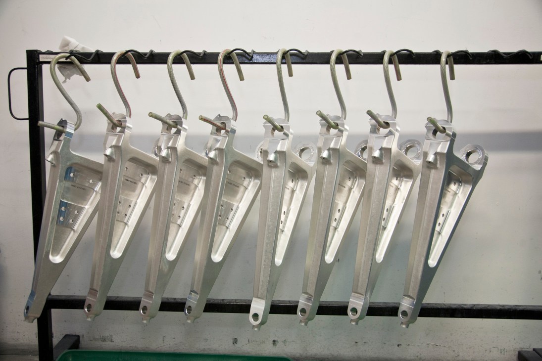 Multiple metallic aircraft chassis components hanging from hooks on a rail at Ultratech Rzeszów.