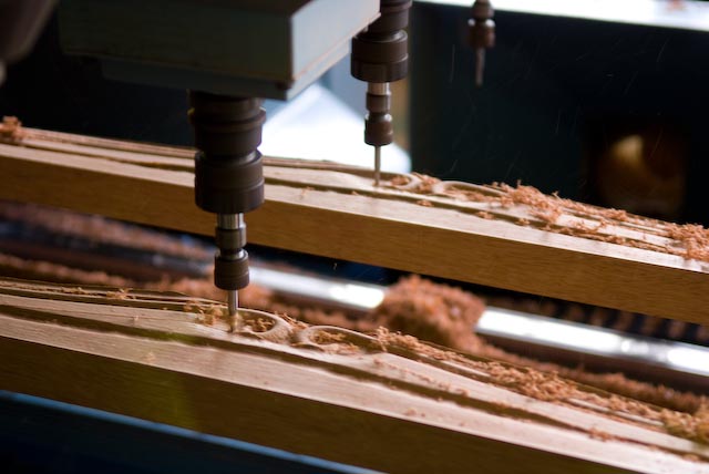Industrial machine tool working on wooden furniture components at Maruni factory.