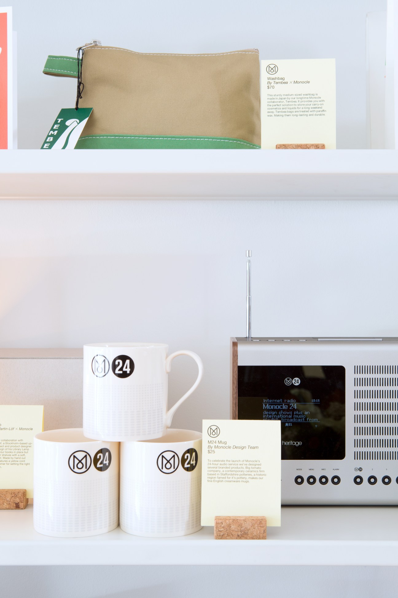 Monocle Revo Heritage G2 radio and M24 branded white cups displayed on a shelf with product information cards.