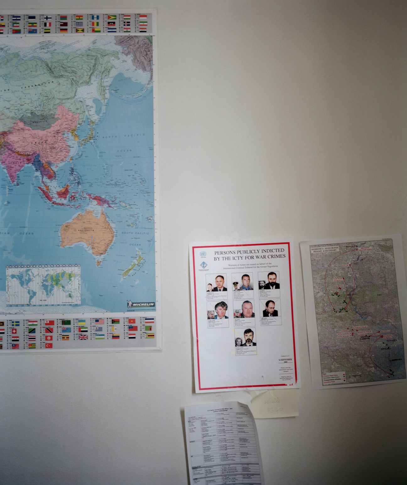 Wall display showing a world map, poster of persons indicted by the ICTY with photographs, and regional maps at the International Criminal Tribunal.