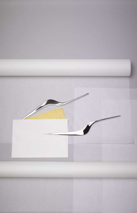 Two steel bird-shaped paper knives by Alessi designed by Giulio Iacchetti, displayed with envelopes and paper.