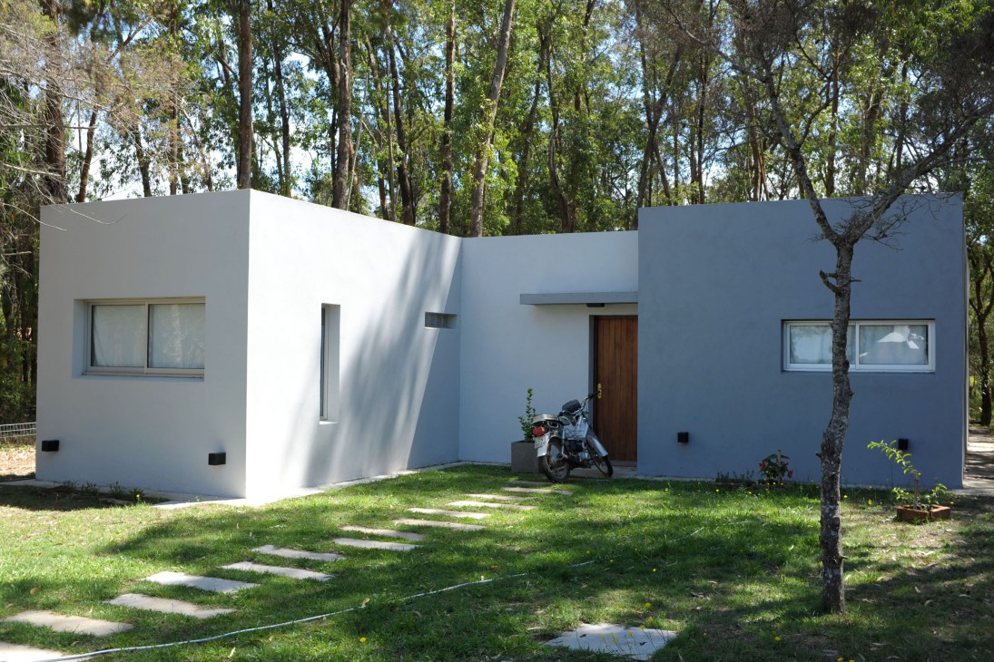 Modern white house with curved walls and large windows surrounded by eucalyptus trees in La Pedrera.