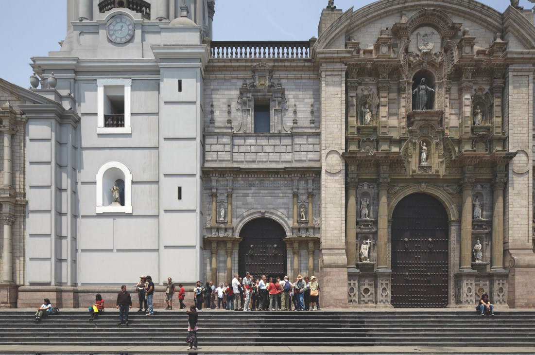 Lima's cathedral facade with ornate stonework and visitors on the steps below.