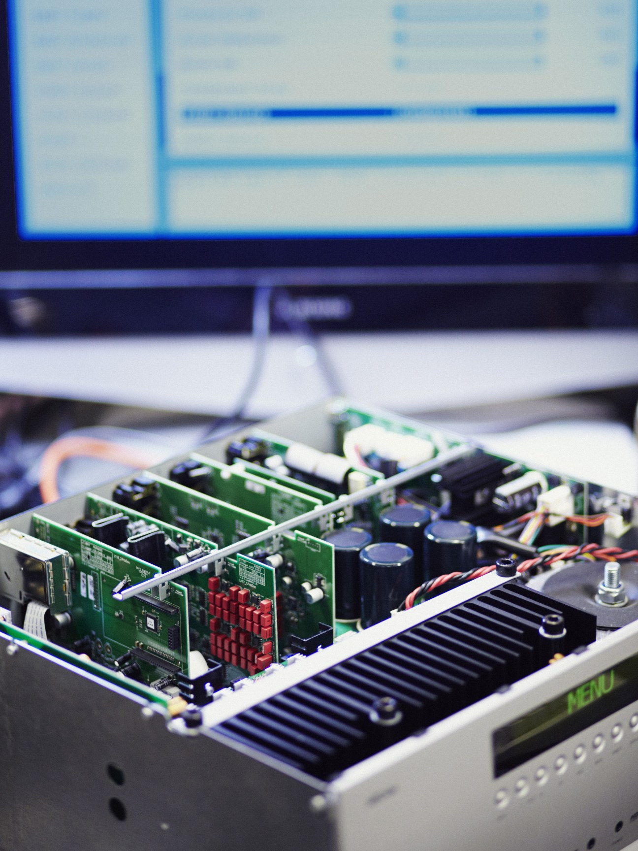 Close-up of green circuit boards with capacitors and electronic components inside an Arcam receiver.