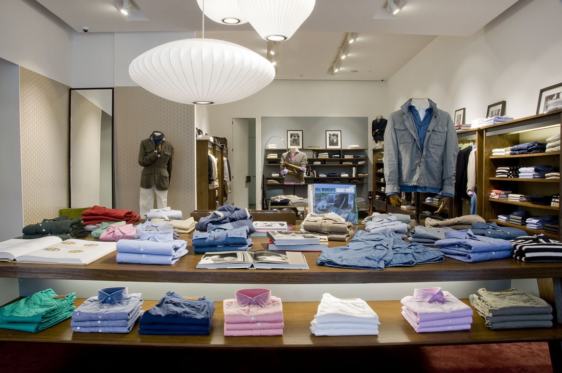 Interior of Slowear menswear boutique in Mexico City displaying folded shirts and clothing on tables and shelves.