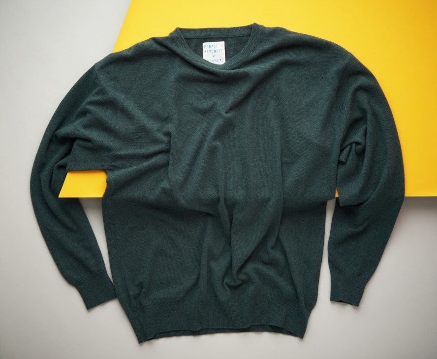 Dark green cashmere crewneck sweater on yellow and white background