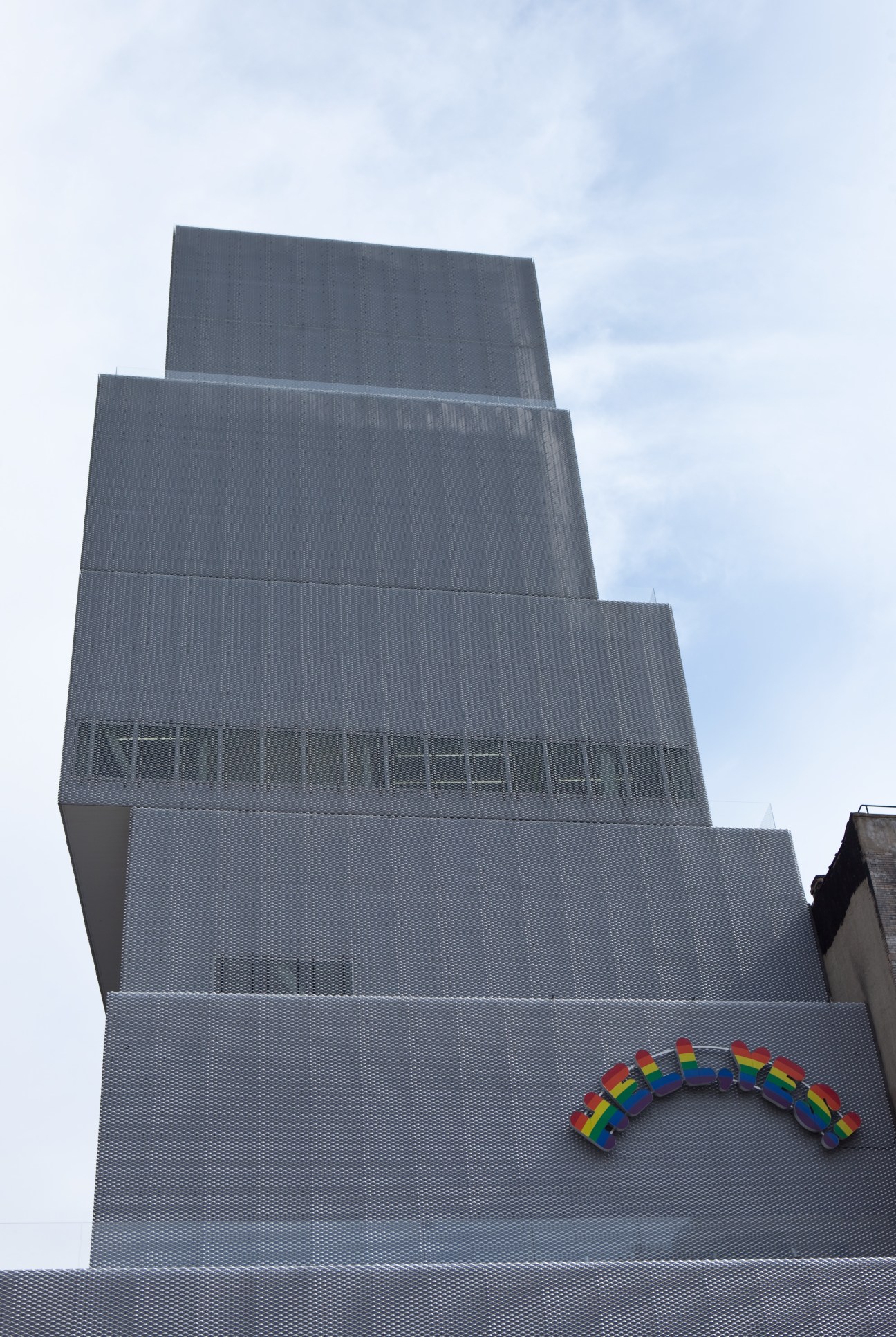 SANNA-designed New Museum building with stacked white boxes and Ugo Rondinone's colorful rainbow 'Hell Yes!' sign on facade.