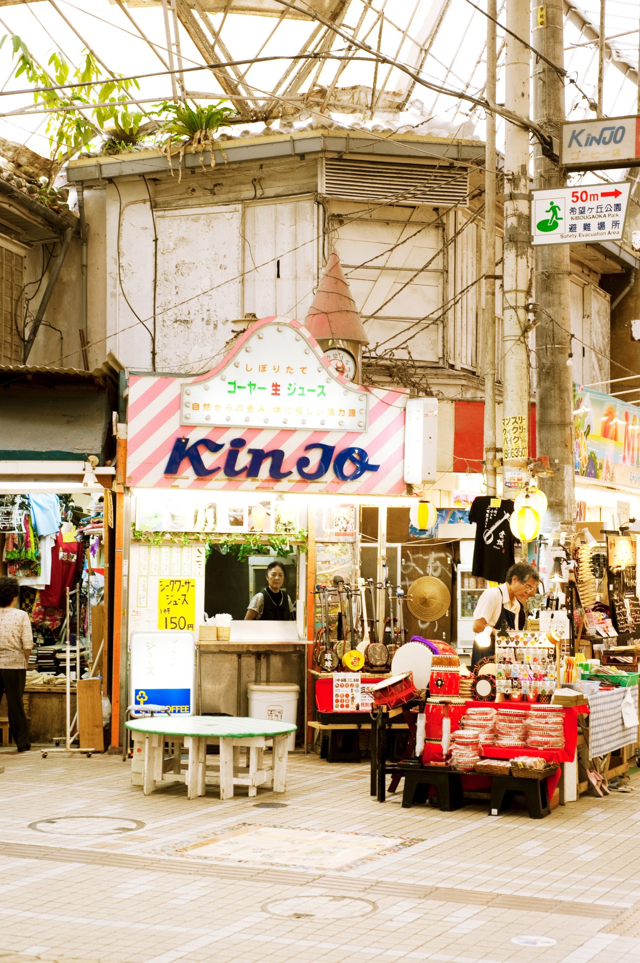 A vintage juice shop with pink striped signage in a covered market arcade in Naha.