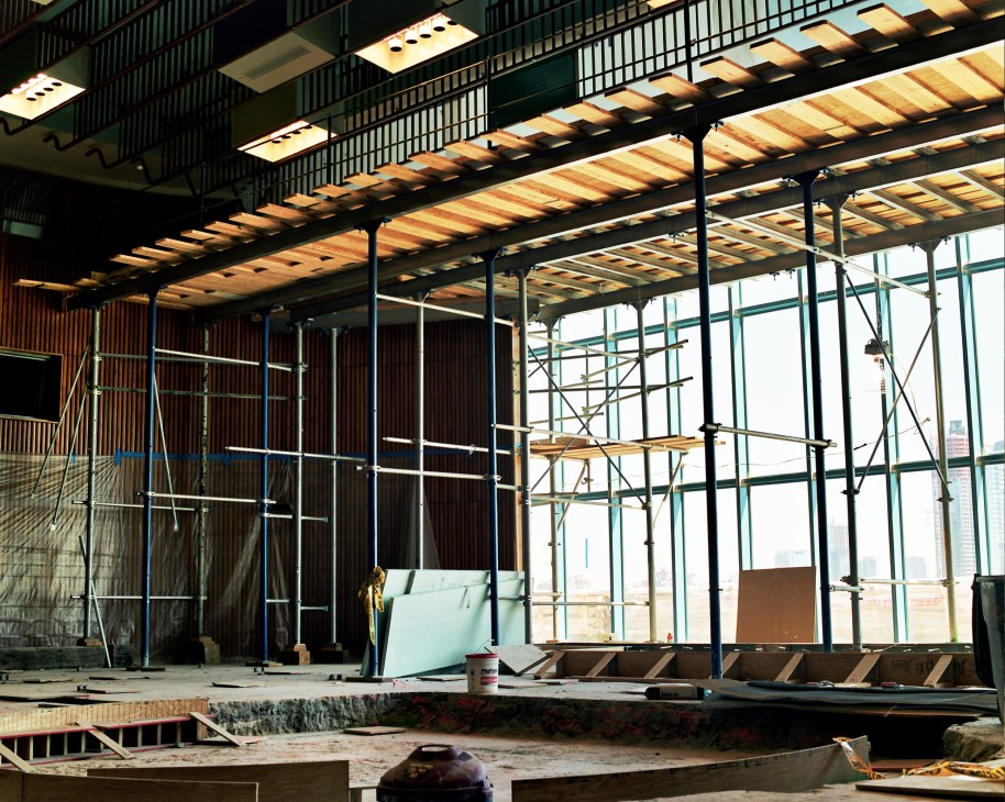 Renovation work underway in the Trusteeship Council Chamber showing wooden panelling, scaffolding, and floor-to-ceiling windows overlooking the East River.