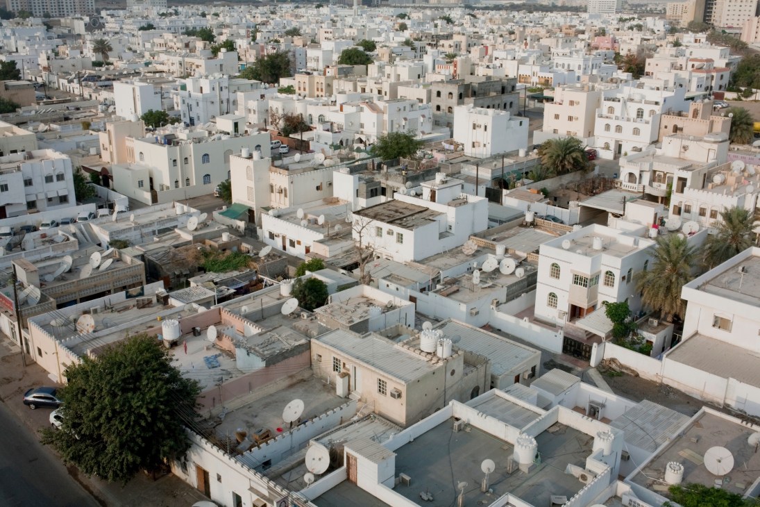Aerial view of Muscat's residential buildings with consistent white and light-colored architecture limited in height.