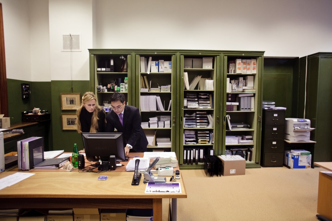 Legal secretary Vilmante Blink and legal counsel Aloysius Llamzon work at a desk in an office with green filing cabinets.