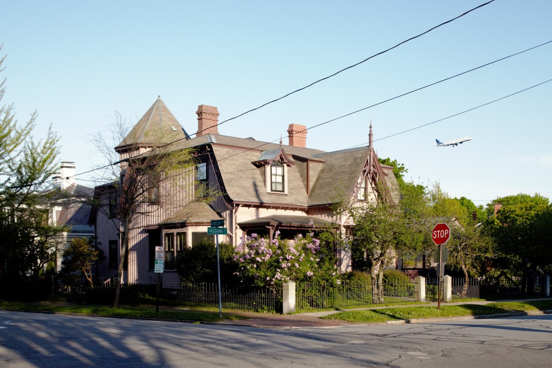 Victorian house with turret, purple flowering shrubs, and white picket fence in West Portland.