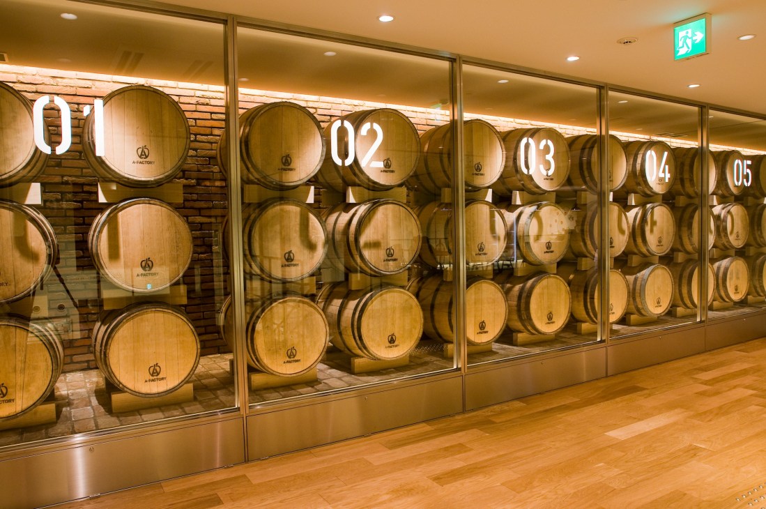 Wooden barrels for apple brandy aging behind glass windows at A-Factory in Aomori.