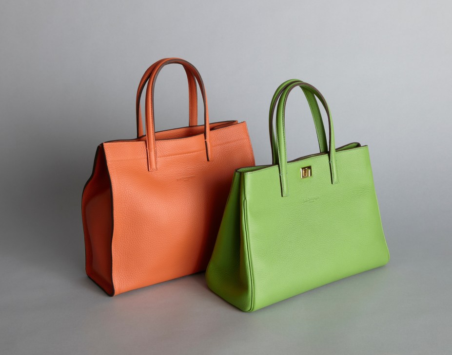 Two colorful leather tote bags by Just Campagne in orange and lime green with handles.