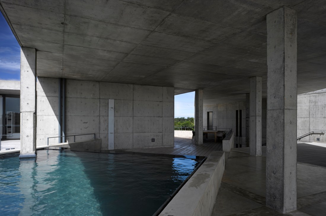 Diagonal infinity pool with turquoise water inside Tadao Ando's concrete Sri Lankan house, overlooking jungle and ocean.
