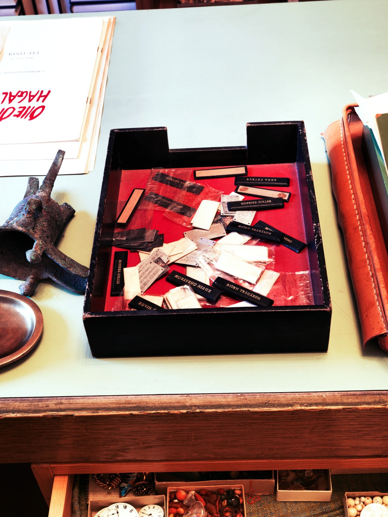 Black box with red fabric containing assorted name tags and labels on Estrid Ericson's desk display.