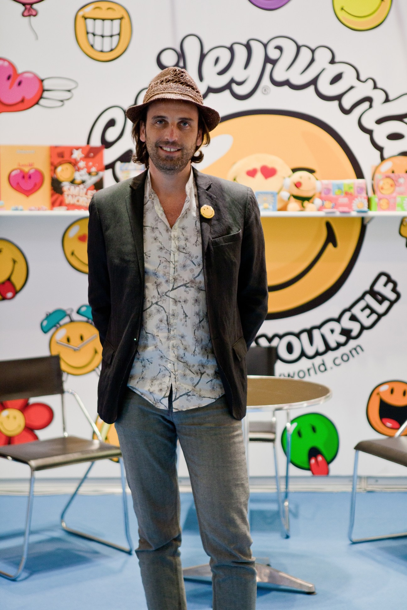 Nicolas Loufrani from Smiley World stands at the Toys & Games Fair booth with colorful smiley face backdrop.