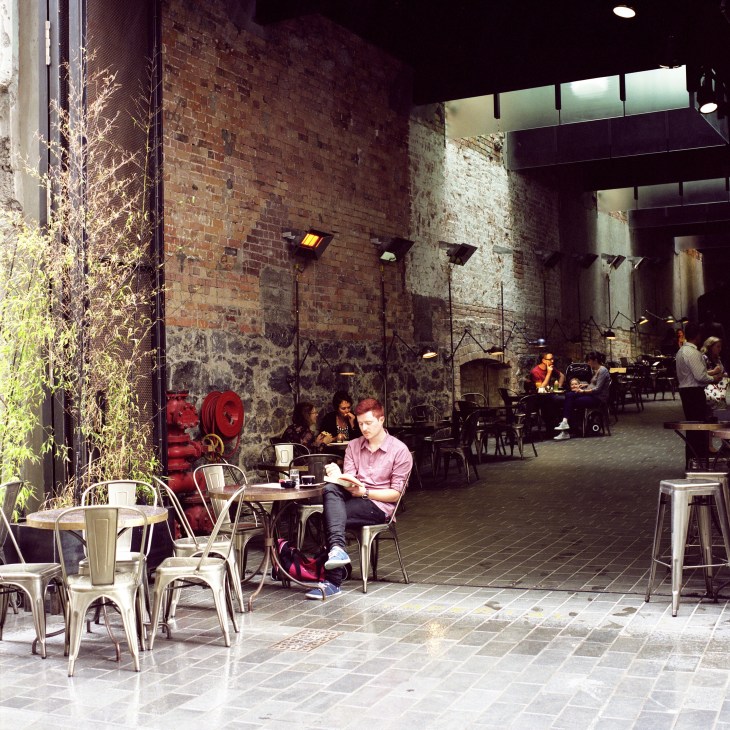 Outdoor courtyard dining area at The Imperial Lane in Auckland with industrial brick walls and metal chairs.