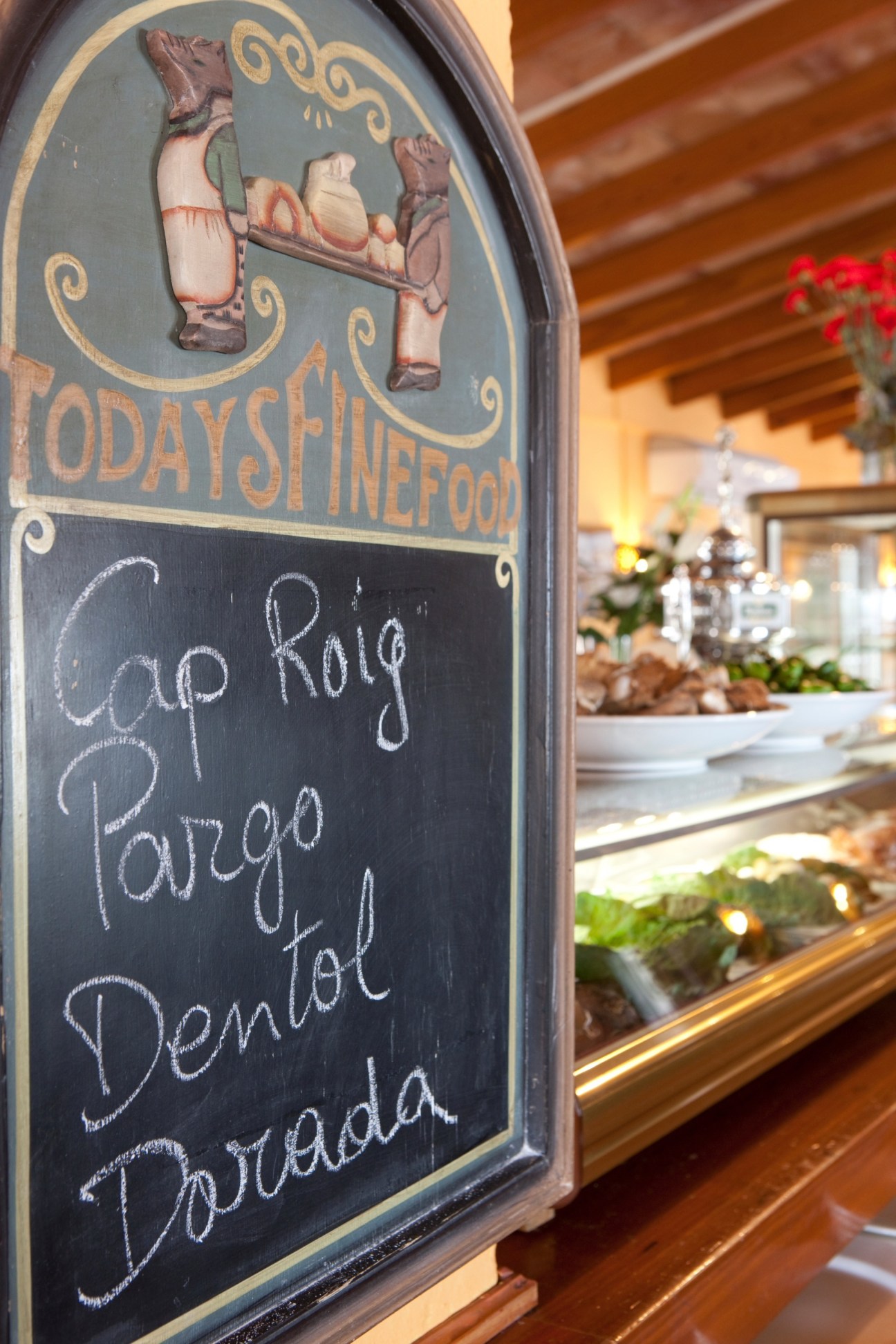 Menu board at El Bungalow seafood restaurant with handwritten specials including Cap Roig, Paella, and Dorada.