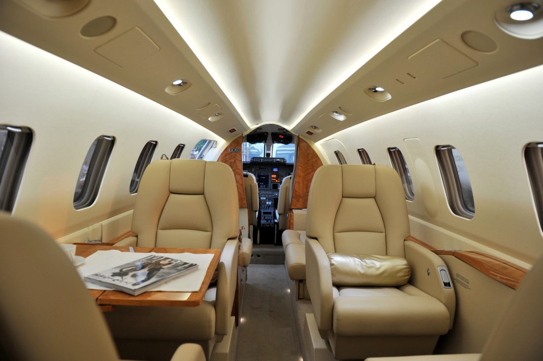 Interior of a Susi Air aircraft cabin with tan leather seats and wood trim facing the cockpit.