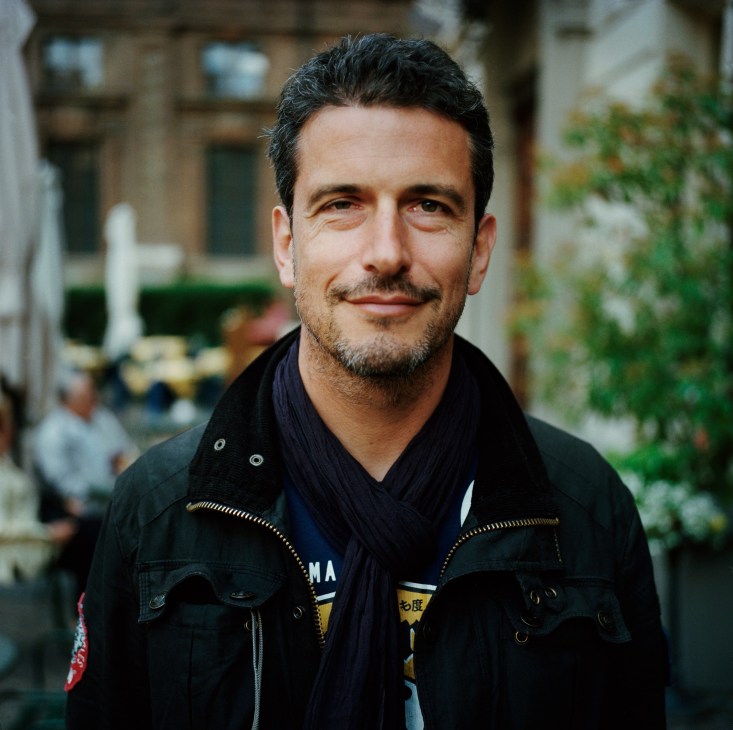 Portrait of Stephan Bourquelos, owner of Gelati Pepino gelato shop in Turin, standing outdoors in a black jacket.