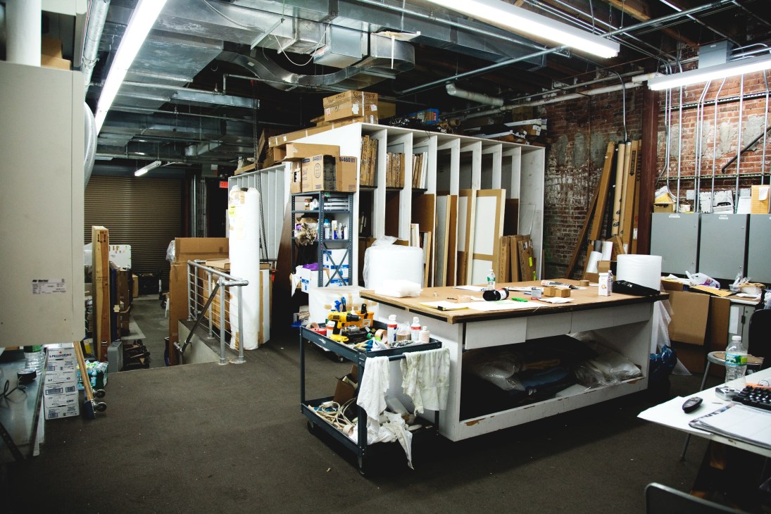 Industrial art storage area with organized shelving, framing materials, and supplies at Pace Gallery.