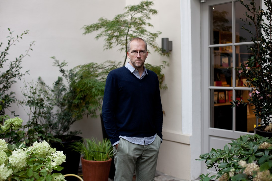 Quintin Leeds, art director at XXI magazine, standing in a courtyard surrounded by potted plants.