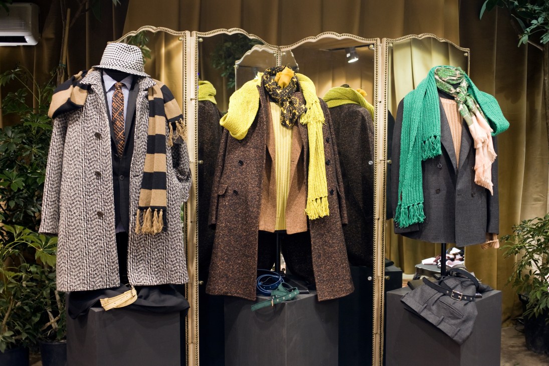 MP fashion installation displaying menswear outfits on mannequins with decorative mirror backdrop.