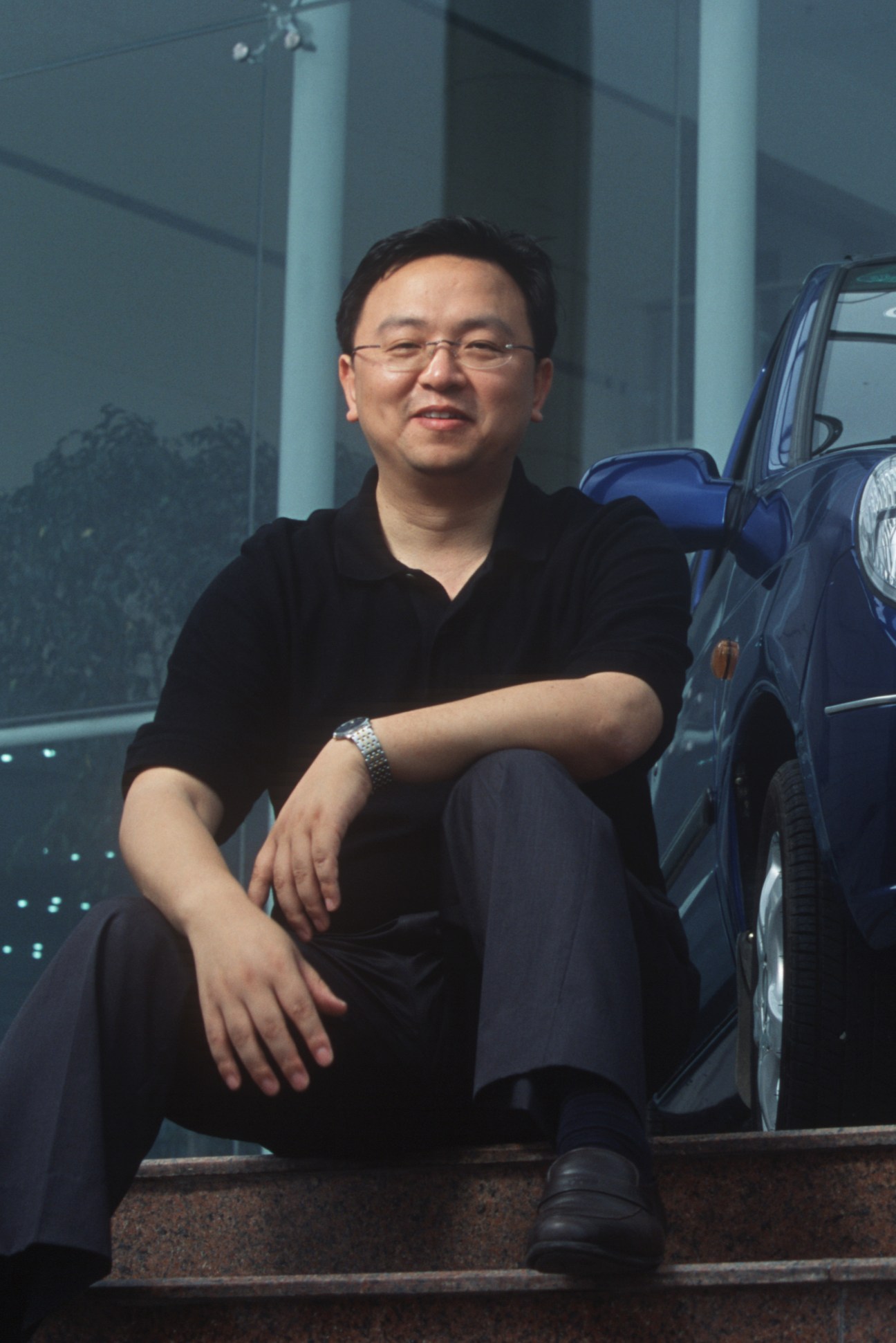 BYD CEO Wang Chuanfu poses beside a blue vehicle at the company headquarters.