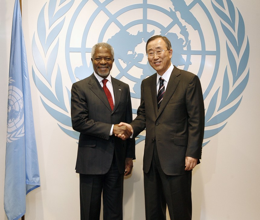 Kofi Annan and Ban Ki-moon shake hands in front of the UN emblem.