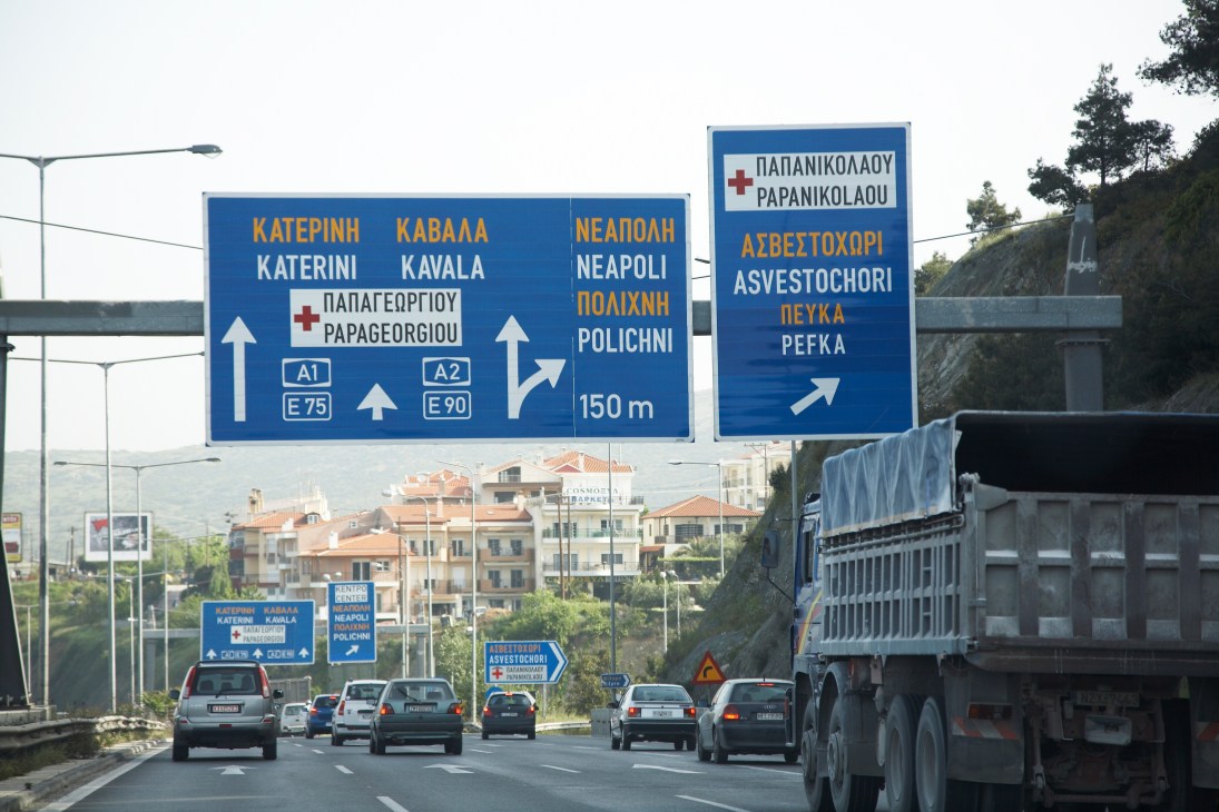 Highway traffic beneath blue directional signs with Greek text on the Egnatia motorway.