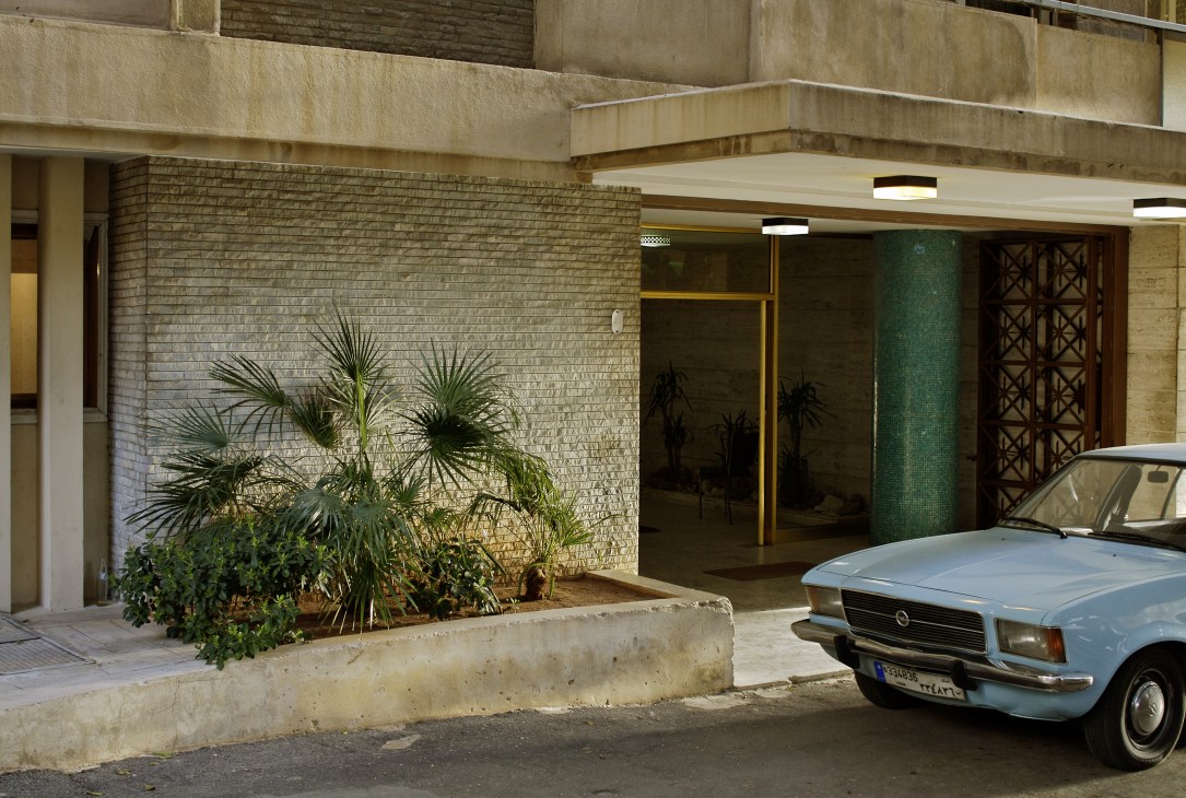 Residential entrance in Sioufi area of Ashrafieh showing modernist architecture with brick facade, plants, and a parked vintage car.