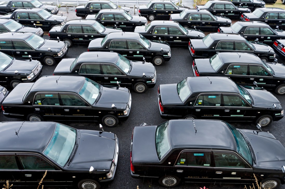 Rows of black and white Tokyo taxicabs parked in a lot awaiting retirement after six years of service.