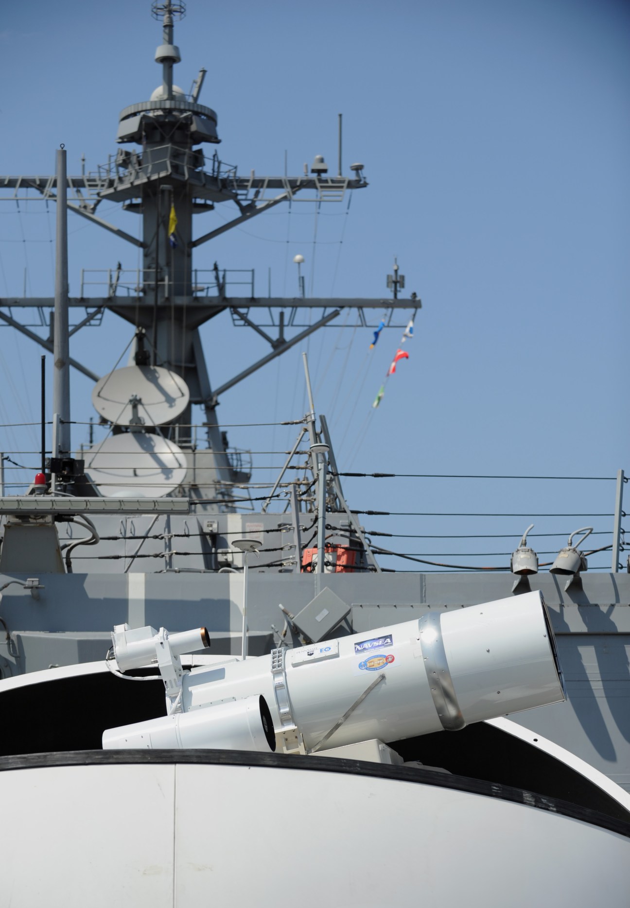 US Navy warship displaying the Laser Weapon System mounted on deck with communication equipment and masts visible.