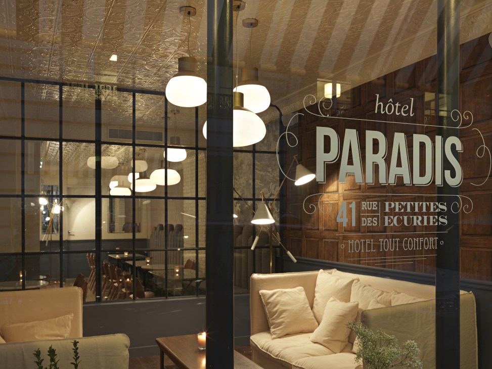 Hotel Paradis storefront in Paris with signage and seating visible through large windows.