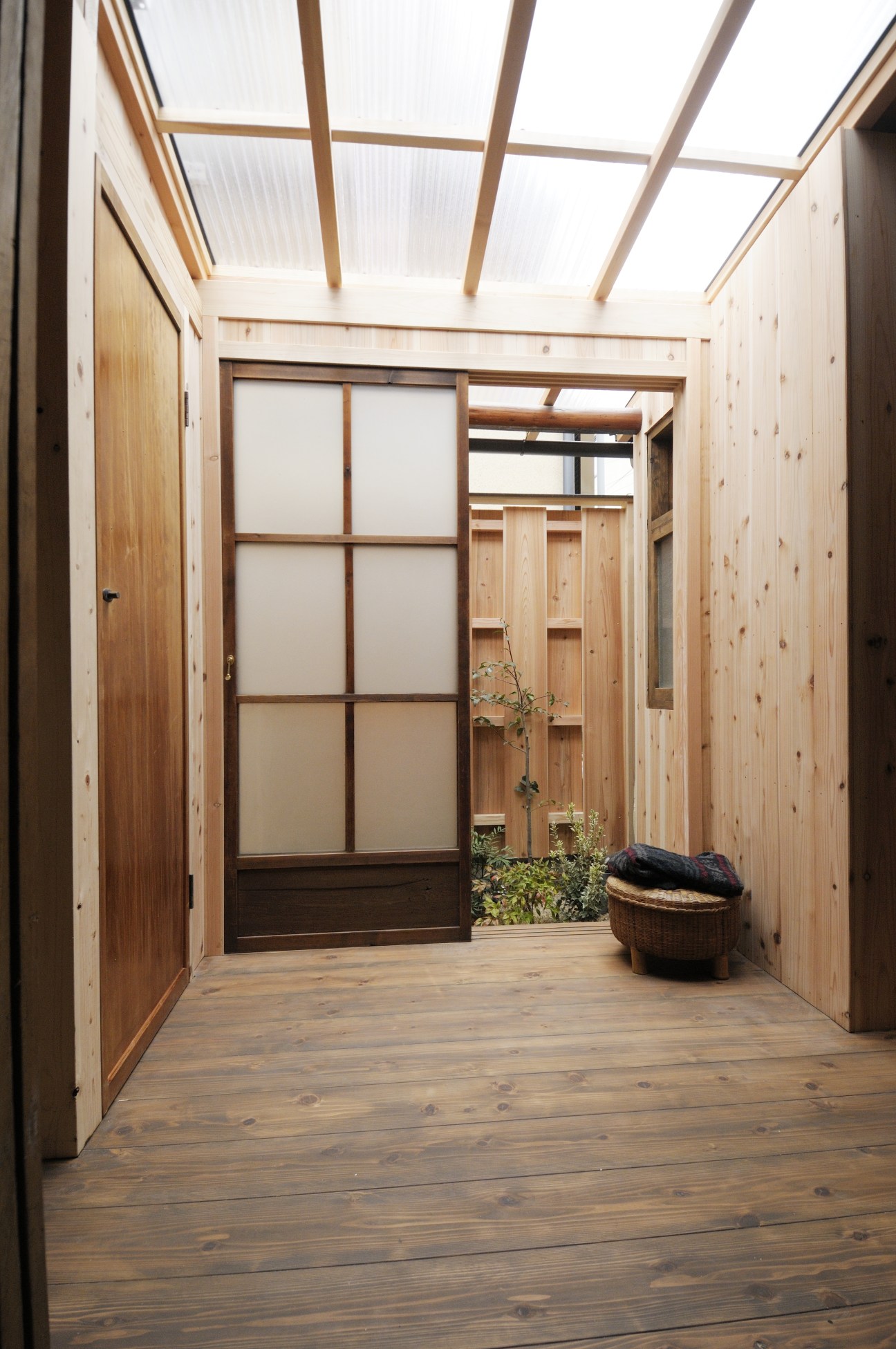 Bright modern sunroom with wooden walls, skylights and glass doors opening to a small garden area.