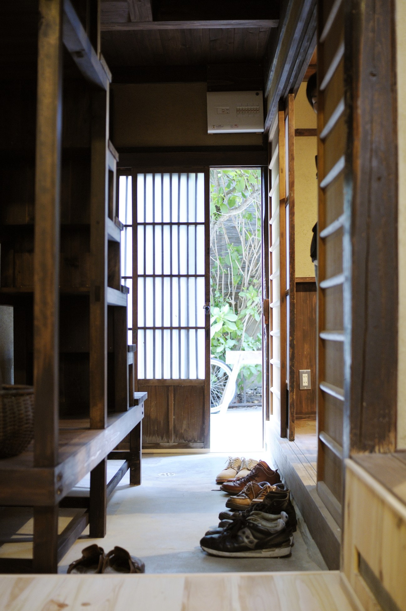 Interior hallway of a renovated Kyoto machiya showing wooden architecture, traditional screens and garden view.