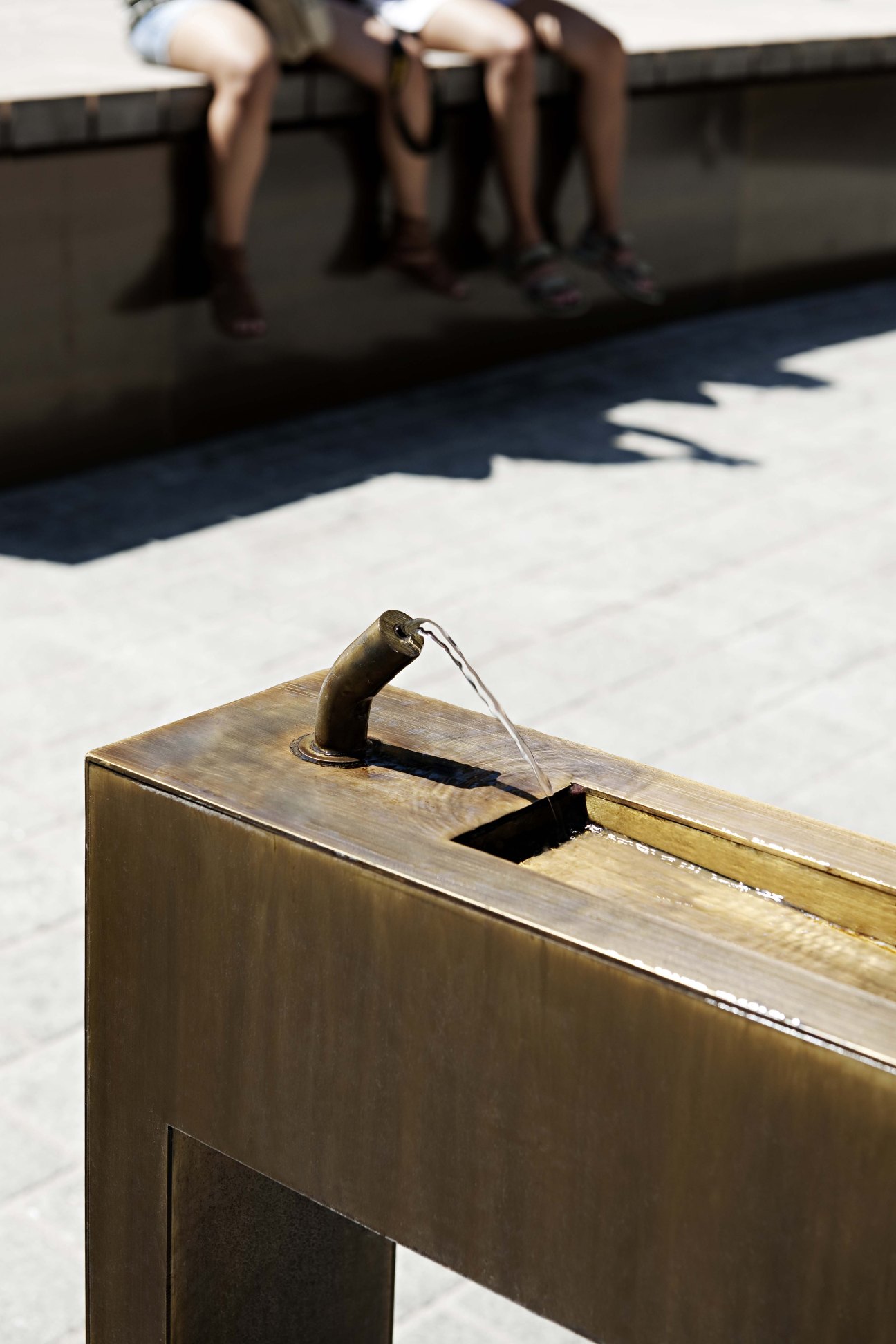 Water fountain detail on Maria-Theresien-Strasse in Innsbruck, with pedestrians blurred in background.