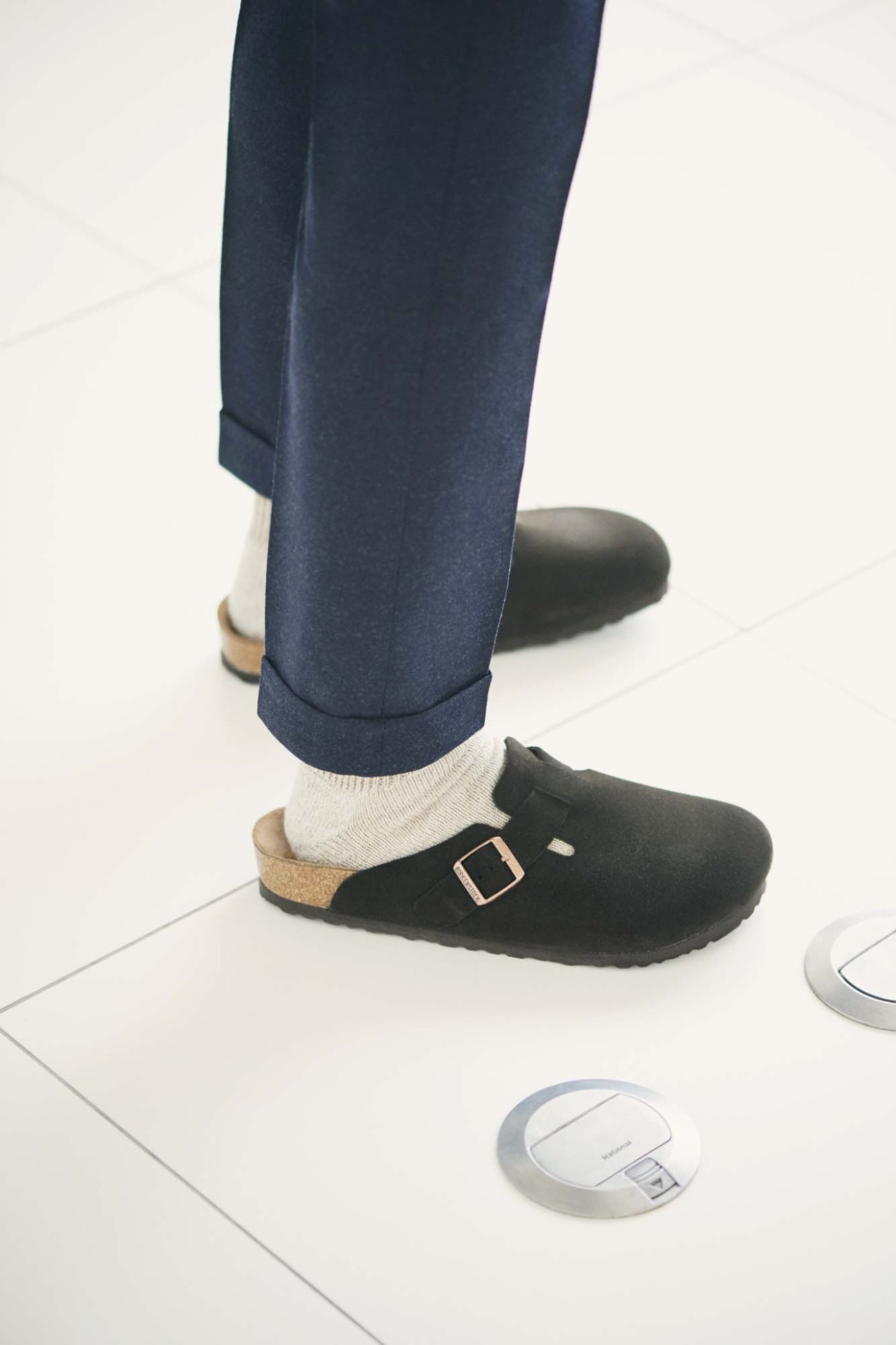 Casual business attire showing tailored navy trousers paired with Birkenstock clogs and white socks.