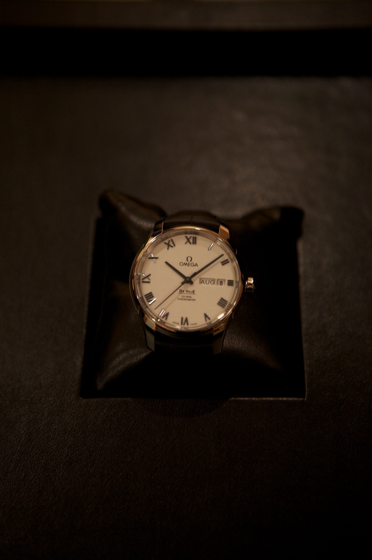 Omega De Ville watch with cream dial and Roman numerals on black leather display block
