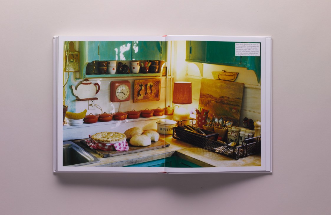 Open book displaying a colorful kitchen interior with cluttered countertops and wall-mounted items.