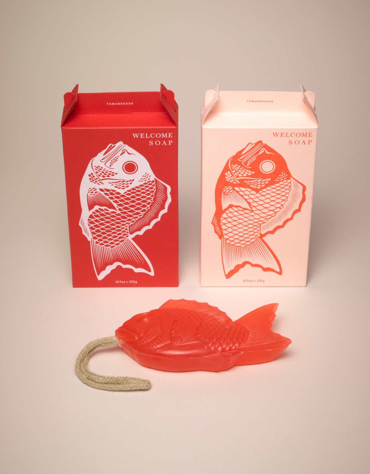 Tamanohada soap packaging boxes in red and pink with fish illustrations, displayed with a red fish-shaped soap-on-a-rope.
