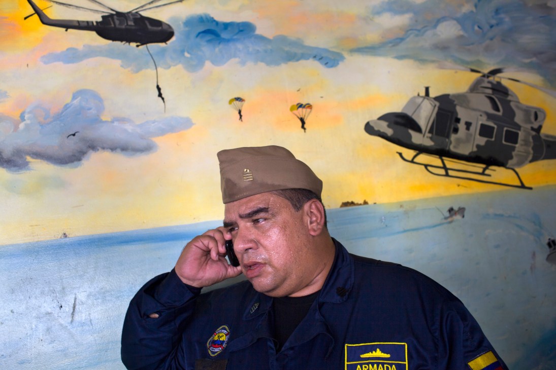 Gabriel Marín, head of Colombia's Pacific coastguard, speaks on phone in front of military mural.