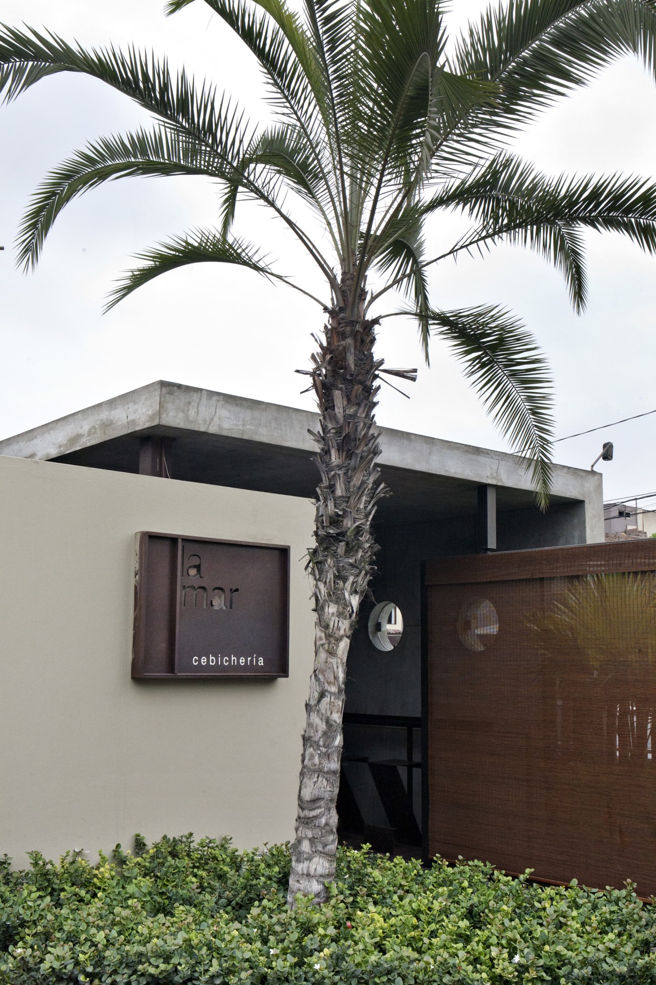 Exterior of La Mar cevicheria with palm tree and modern architecture in Lima