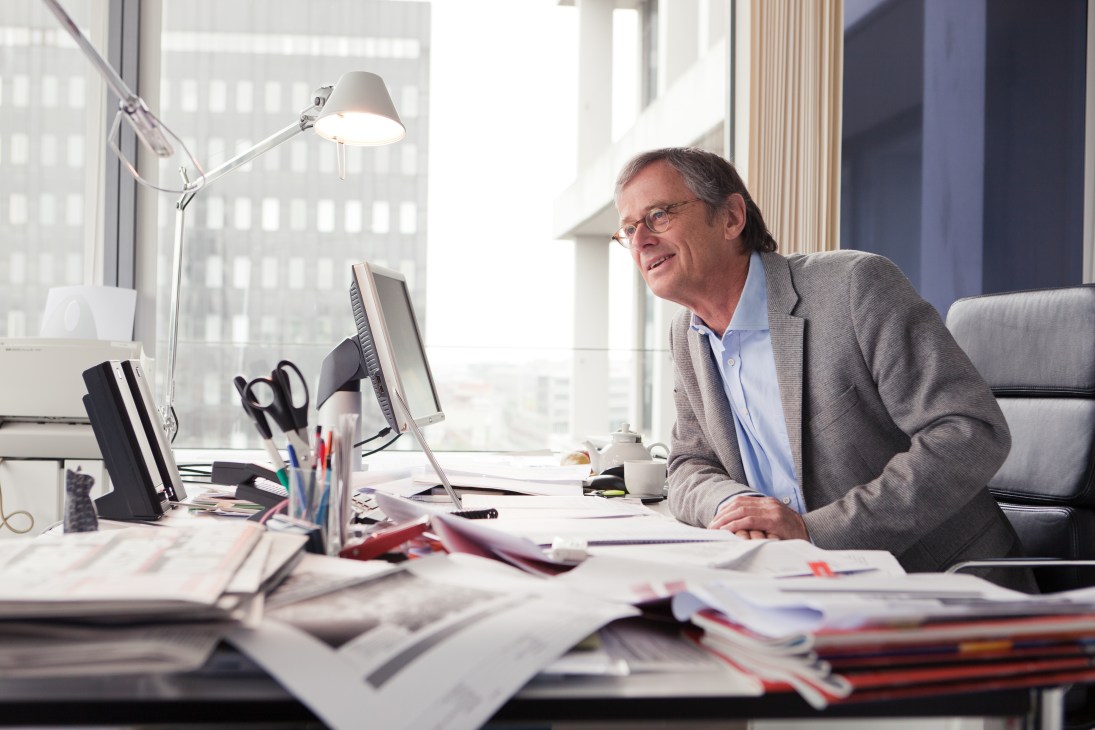 Senior editor Hans-Ulrich Stoldt at his desk in a high-rise office with city views.
