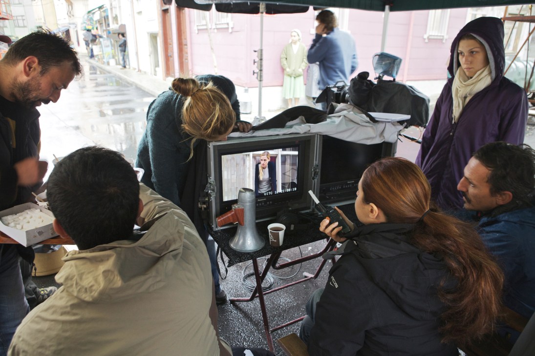 Director Deniz Kalas reviews footage on a monitor during filming on an Istanbul street location.
