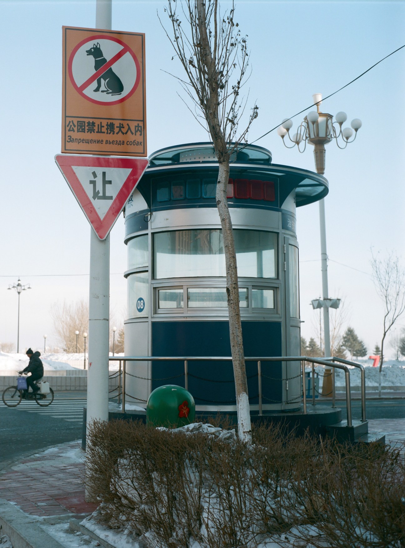 Cylindrical traffic police booth in Heihe with no-dogs sign and multilingual text on pole.