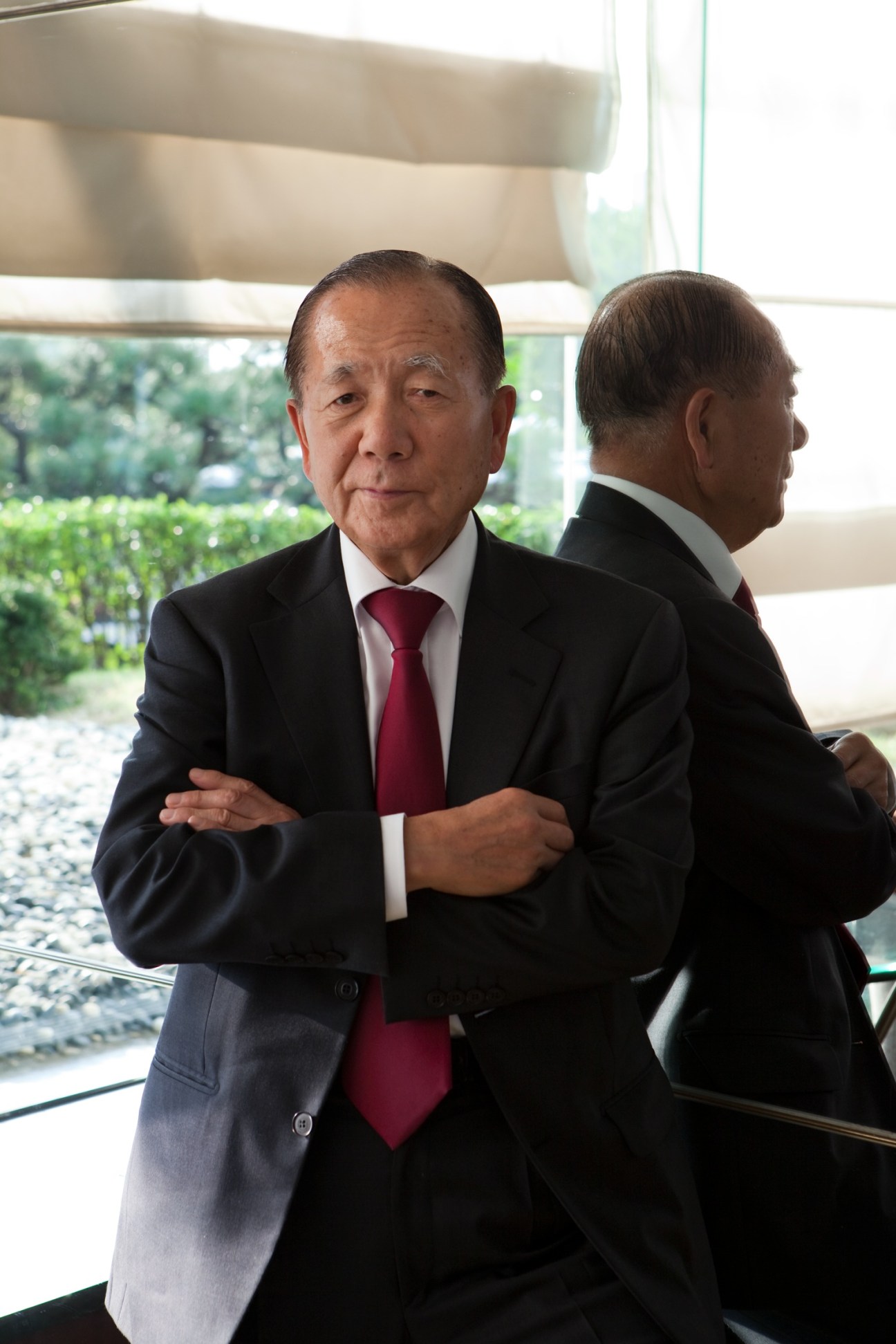 Film festival director Kim Dong-ho in a black suit with red tie standing by a window.